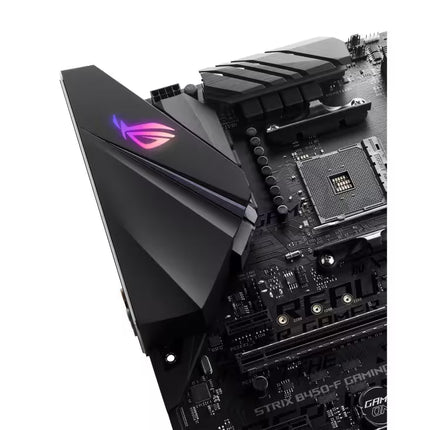 Close-up of a black ASUS ROG Strix B450-F gaming motherboard with a prominent angular black heatsink featuring the illuminated RGB logo in pink and purple, set against a plain white background.