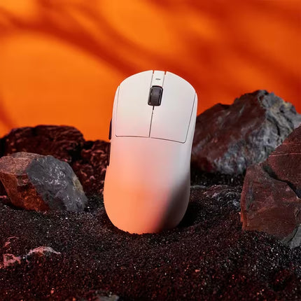 White computer mouse on a bed of dark sand with an orange-brown gradient background
