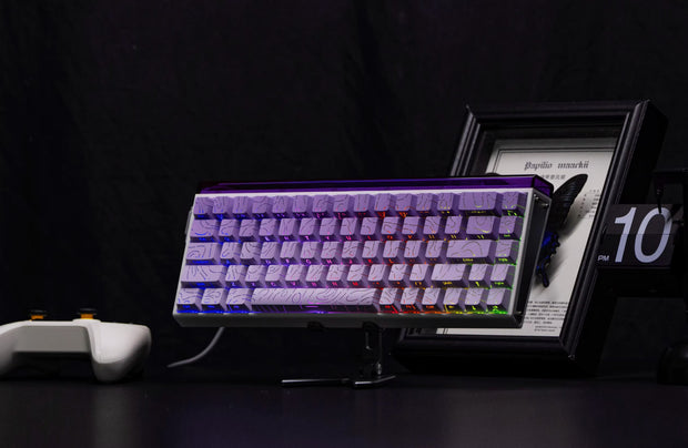 Gaming keyboard with RGB lighting on a dark surface, next to a framed picture and controller.