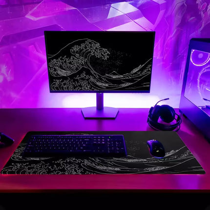 Modern desk setup with computer monitor, keyboard, mouse, and headphones under purple LED lights.