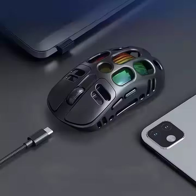 Gaming mouse with colorful buttons on a dark surface next to a smartphone and laptop.