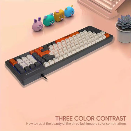 Mechanical keyboard with three color contrast design on a pink surface, surrounded by small decorative items.