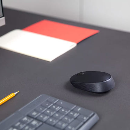 The Logitech M171 wireless mouse placed on a modern office desk beside a keyboard, monitor, and pencil, illustrating a clean and productive workspace setup.
