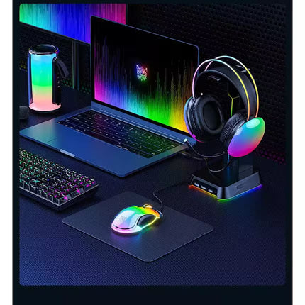 Gaming setup with laptop, keyboard, mouse, and headset on a desk with RGB lighting.