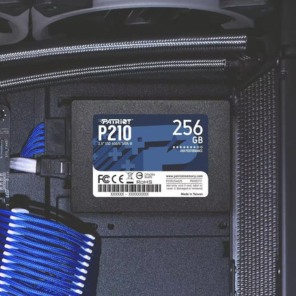 A Patriot P210 256GB SSD installed inside a computer case, shown with blue and white cable ties and black internal components.