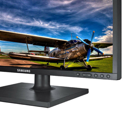 Samsung monitor displaying an image of a biplane on a grassy field with a blue sky.