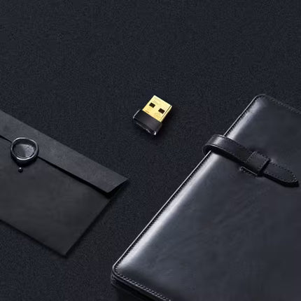 Black USB device on a dark surface with black leather-bound books.
