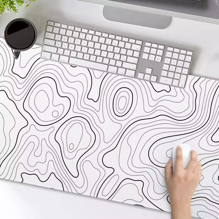 Desk setup with a topographic design desk mat, keyboard, and mouse.