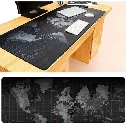 A large rectangular desk mat with a dark world map print is shown on a wooden desk, with a monitor, keyboard, and mouse placed on top. A second, cleaner view of the same desk mat appears below the main scene.