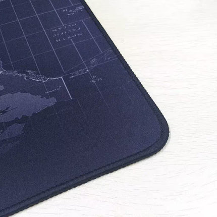 A close-up of a dark navy blue gaming mouse pad with a subtle world map grid design, resting on a light-colored wooden surface.