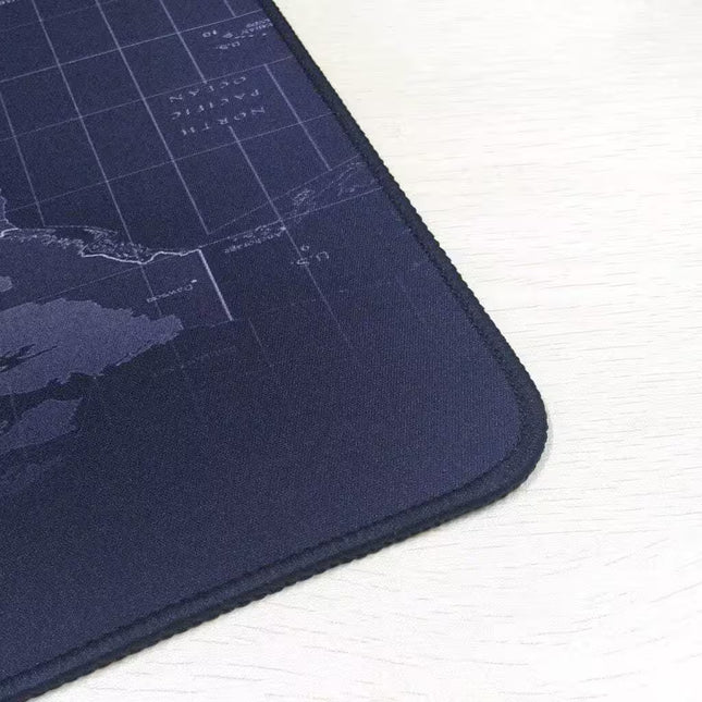 A close-up of a dark navy blue gaming mouse pad with a subtle world map grid design, resting on a light-colored wooden surface.