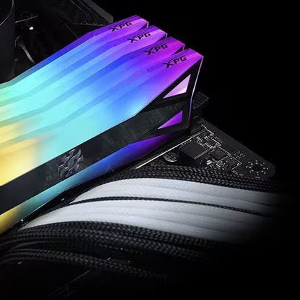RGB-lit DDR4 RAM memory modules with a gold, blue, and purple gradient heat spreader, shown installed on a motherboard.