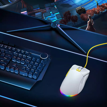 Gaming keyboard and mouse on a dark surface with a computer screen displaying a game.
