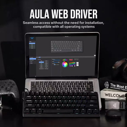 AULA Web Driver software shown on a laptop screen with a keyboard and mouse in front, set on a dark desk with gaming accessories and text reading 'AULA WEB DRIVER'.