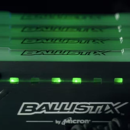 Close-up of Ballistix computer memory modules with green LED lights on a black background.
