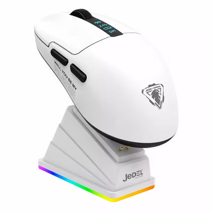 A white JEDEL wireless gaming mouse with black accents, resting on a matching white charging dock that features a multicolor RGB light strip. The mouse has a sleek ergonomic design with a black scroll wheel, side buttons, and a silver JEDEL logo on the side.