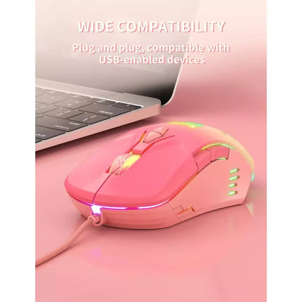 A pink wired gaming mouse with RGB rainbow lighting, shown next to a laptop on a pink surface with text reading 'WIDE COMPATIBILITY' and 'Plug and plug, compatible with USB-enabled devices.'.